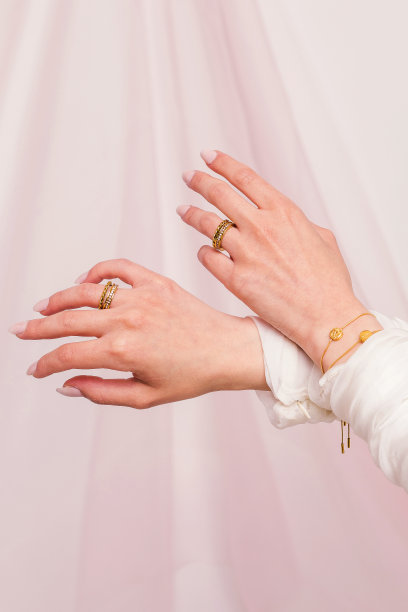 美丽的女人的手，带着戒指和手镯，对着粉红色的窗帘。美丽的情人节礼物。图片下载