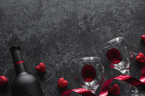 瓶葡萄酒，红丝带和杯子与红酒情人节浪漫的概念与地方的文字在黑暗的背景图片下载