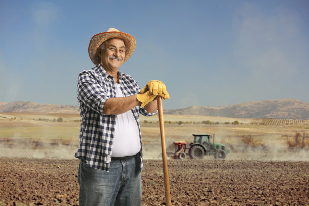 戴草帽的农民站在有拖拉机的田野上图片下载