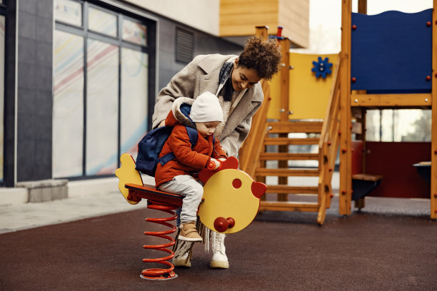 一个年轻的女人在操场上逗三岁的男孩玩。图片下载