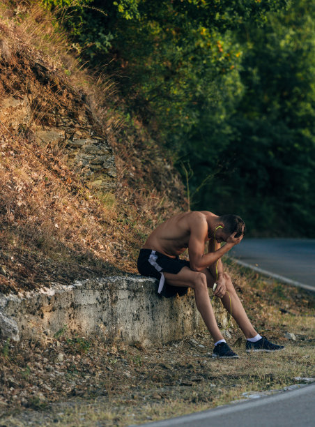 疲惫的运动员戴着耳机坐在户外休息图片下载