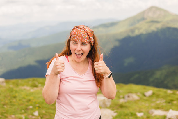 年轻女子竖起大拇指表示成功。在山谷的背景下。在山里旅行。自由,旅游的概念图片下载