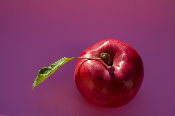 红苹果，绿色的叶子，深粉红色的背景。图片下载