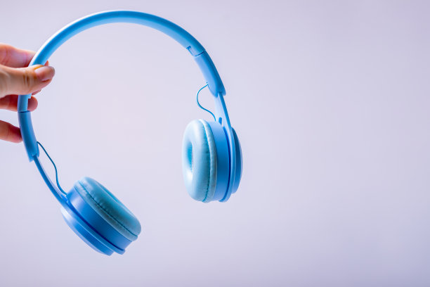 手拿无线耳机，蓝色耳机，隔离。单色照片与空间的文字为设计师。音乐与科技概念图片下载