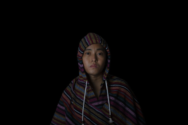 男子身穿外套，头戴兜帽，背景为黑色。时尚概念和时尚男性。图片下载