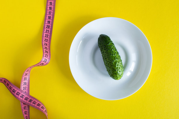 生黄瓜在白色的盘子和粉红色厘米黄色的背景。前视图。图片下载