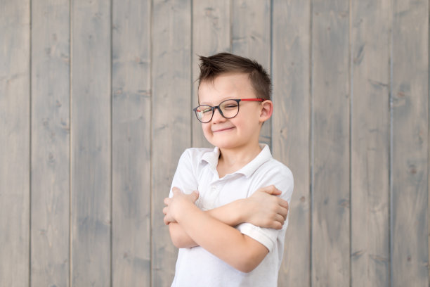 木制背景的小男孩戴眼镜和白色t恤的肖像。一个有想法的孩子。准备上学图片下载