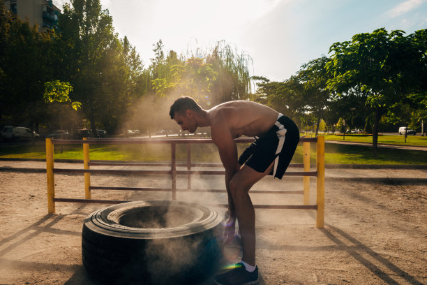 肌肉发达的运动员在街头健身房用大轮胎训练图片下载