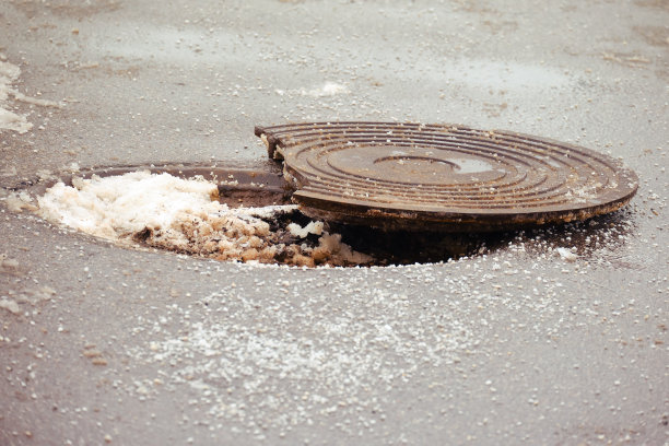 冬季沥青路上一个裂开的检修孔图片下载