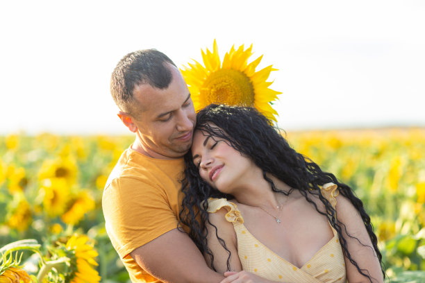 一对美丽的年轻夫妇，一男一女，在夕阳下的向日葵地里拥抱。图片下载