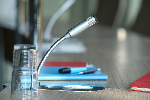 传播、媒体和新闻概念:在办公室、会议厅或会议室的桌子上，麦克风与笔记本、纸张、文件、文件和写作材料的特写图片下载