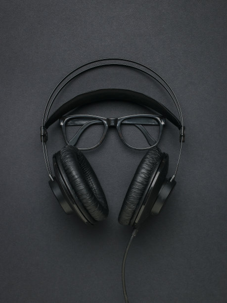 黑色背景上的黑色耳机和经典的黑色眼镜。平的。图片下载