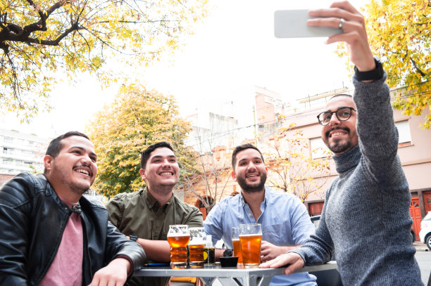 一群朋友坐在酒吧外面喝啤酒自拍。图片下载