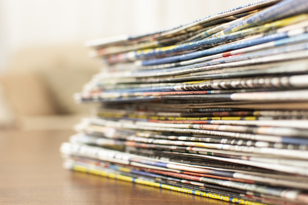 木桌上放着一堆背景模糊的报纸，还有文字的复印空间。图片下载