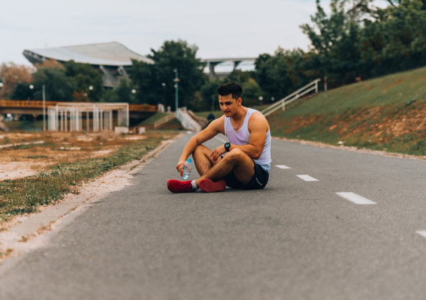 一个年轻人在跑步后放松下来喝水图片下载