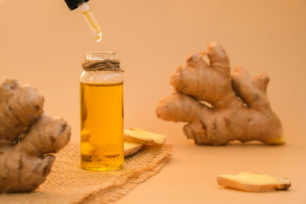 玻璃瓶的生姜精油，姜根在米色背景。健康替代品。天然化妆品成分，护肤、护身、护发图片下载