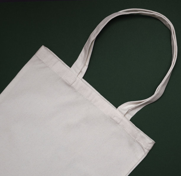 模拟环保米色或白色帆布棉织物手提袋上深绿色的背景。购物袋模型空白模板。可重复使用的杂货和购物袋。图片下载