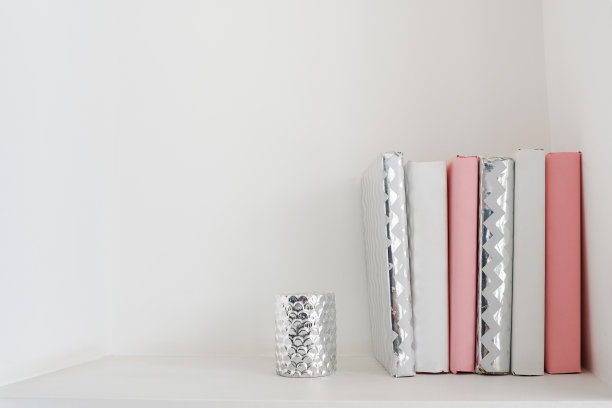 一堆白色和粉红色的书放在书架上，白色的墙壁作为背景。本空间图片下载