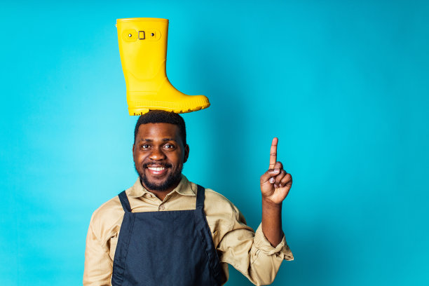 尼日利亚园丁男子展示了蓝色工作室的黄色胶鞋准备秋春季节图片下载