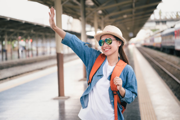 人像美丽的女人旅行者游客手挥动背包在火车站素材图片