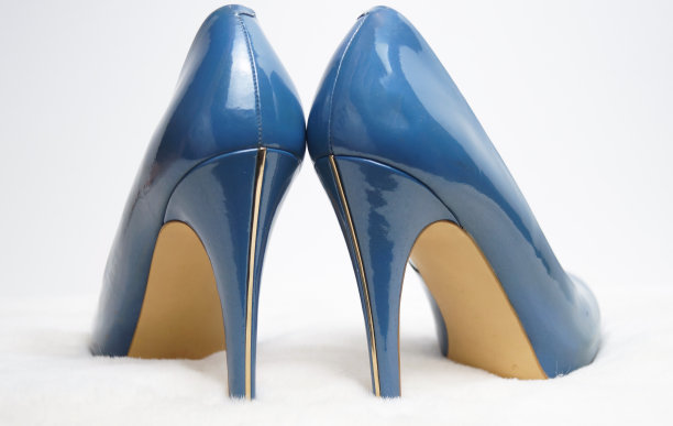 白色毛皮地毯上的蓝色高跟鞋。图片下载