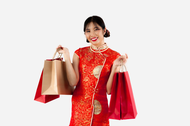 亚洲妇女穿着红色旗袍，拿着购物袋孤立在白色的背景上。中国新年在购物概念风格。图片下载