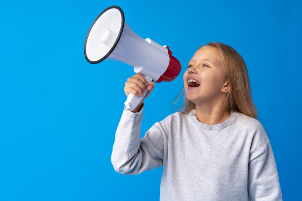 小女孩在蓝色背景下使用扩音器图片下载