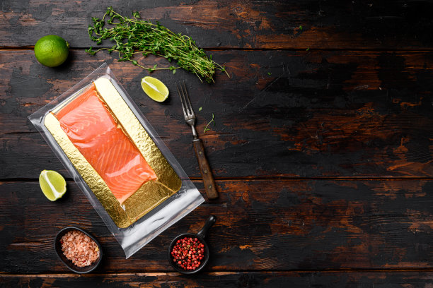 鲑鱼片在真空包装，与草药，在旧的深色木制桌子背景，俯视图平躺，与文本复制空间图片下载