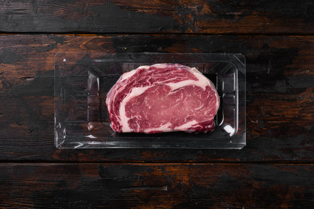生牛排在一个托盘，在旧的深色木制桌子背景上，俯视图平躺，与文本复制空间图片下载