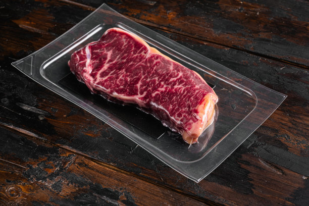 真空包装生纽约striploin牛排，在旧的深色木制桌子背景上，与文本的复制空间图片下载