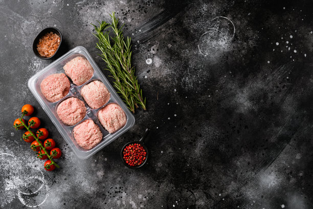 生火鸡肉丸在塑料一次性托盘，黑色黑色石头桌子背景，俯视图平躺，与文本复制空间图片下载