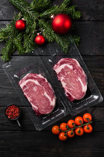 牛排，肋眼肉，真空包装到圣诞节和新年，在黑色木制的桌子背景下，俯视图平躺图片下载