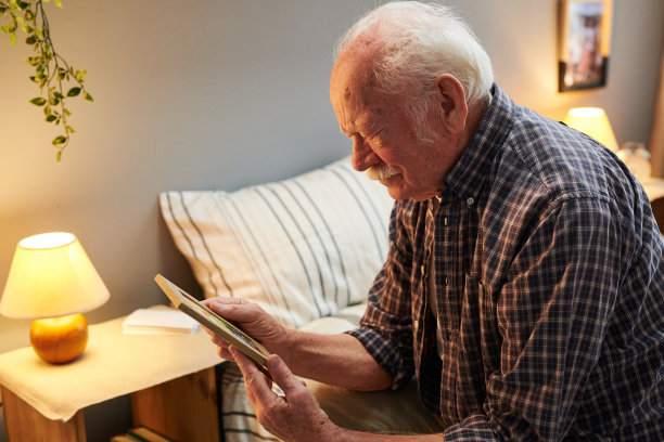 灰白头发和小胡子的老人看着相框里的照片图片下载