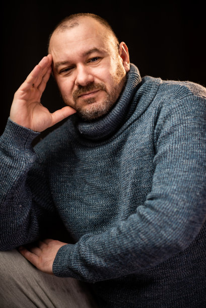穿毛衣的中年男子看着镜头。相貌正常的未刮胡子男子。图片下载