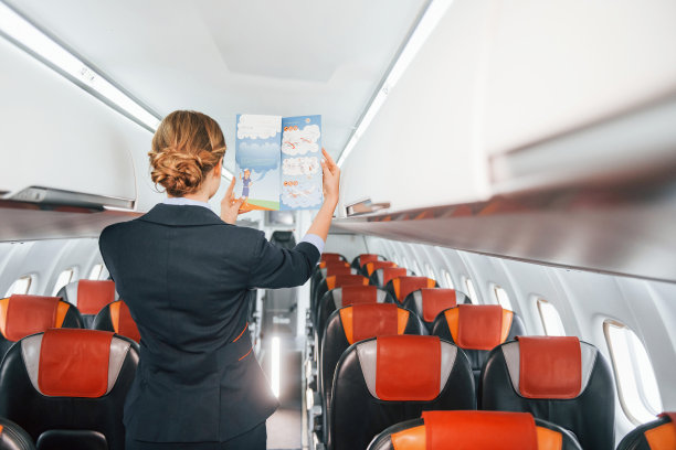 持有有说明的纸张。年轻的空中小姐在客机上工作图片下载