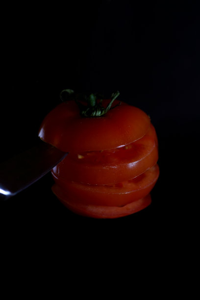 飞行食物的概念-切西红柿和刀悬浮在黑色的背景上图片下载