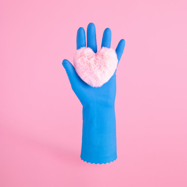戴着蓝色手套的女性手在粉红色的背景下握住毛茸茸的心。创造爱或健康的观念。图片下载
