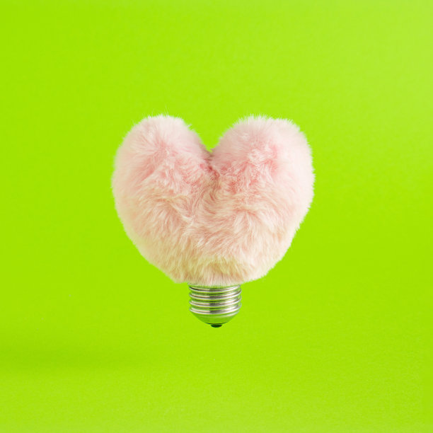 创意粉红心作为一个灯泡对绿色柔和的背景。创意情人节或爱情的概念。平的。图片下载