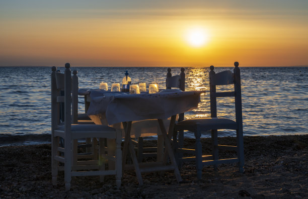 沙滩上的餐桌和落日的背景。日落时美丽的大海的宁静景象。图片下载