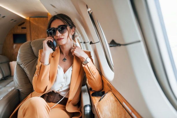 使用手机。穿着黄色衣服的年轻女乘客正在飞机上飞行图片下载