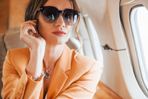 在太阳镜。穿着黄色衣服的年轻女乘客正在飞机上飞行图片下载