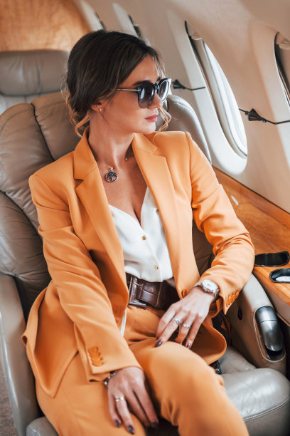 在太阳镜。穿着黄色衣服的年轻女乘客正在飞机上飞行图片下载