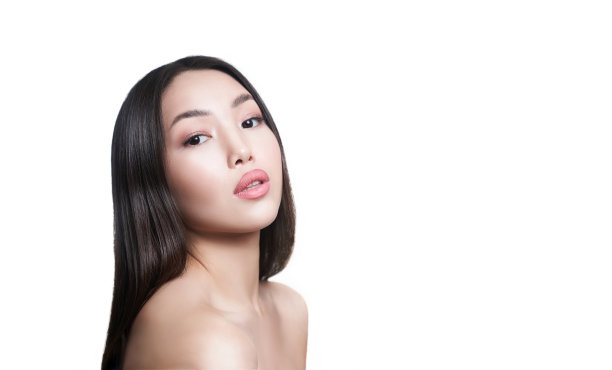 一位年轻的亚洲女性，有着健康的皮肤和紫色的毛茛花。在一个孤立的白色背景与空间复制图片下载