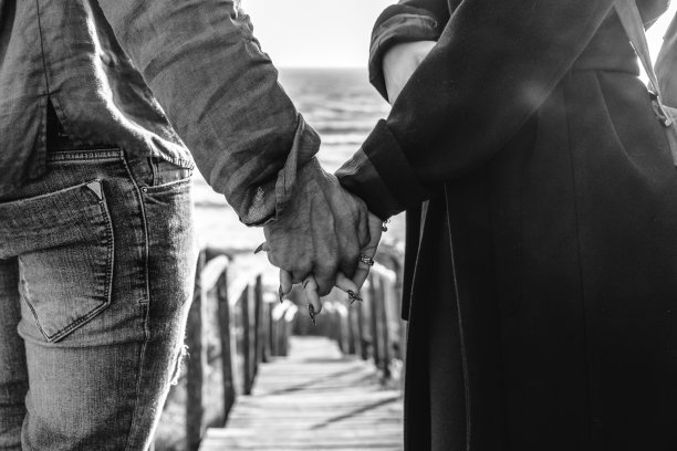 年轻夫妇牵手走下木楼梯走向海滩-潮人夫妇，牵手，在海滩享受浪漫的夜晚-女性的手与美丽的长指甲图片下载