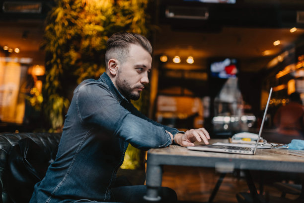 一个人在共同工作的咖啡馆里用笔记本电脑在线工作，在线学习的概念，在互联网上协商工作。图片下载