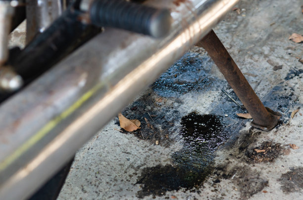 一辆旧摩托车，机油漏到了地上。图片下载