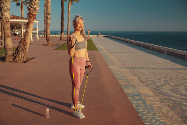 一名女子用健身橡皮筋在路堤上锻炼的全身照片图片下载