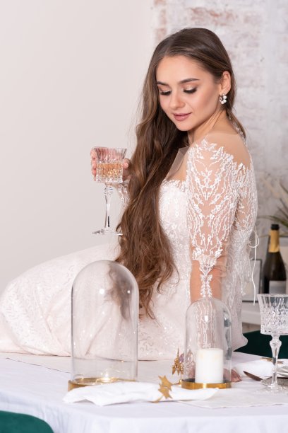 新娘披着飘逸的秀发，在餐桌上，端着一杯美酒。图片下载