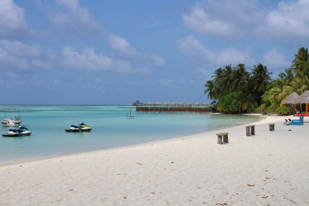 印度洋海岸的白色沙滩，长椅，棕榈树，水上摩托艇，游艇，船和别墅在马尔代夫蔚蓝的水。图片下载