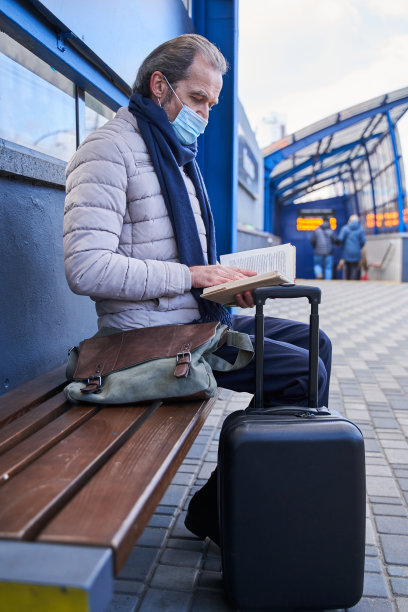 退休男性戴着防护面具，坐着看自己喜欢的小说图片下载